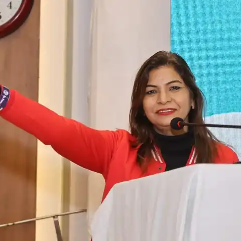 Anu Manocha at the lectern with her arm stretched out, welcoming the audience at a VBG business meet in Delhi