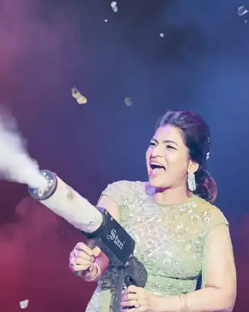 Anu Manocha laughing as she fires a confetti cannon at a celebration