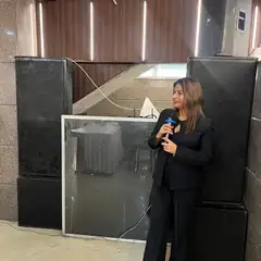 Anu Manocha in a black suit hosting a conference