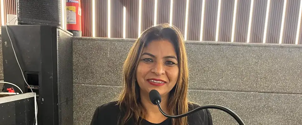 Anu Manocha at a conference lectern with a gooseneck mic