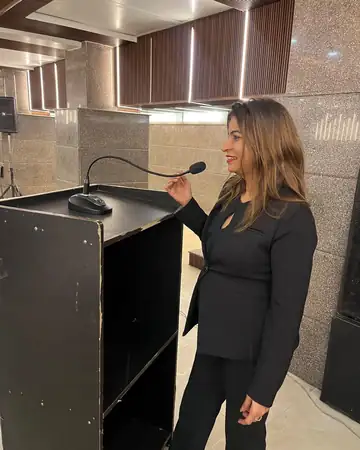 Anu Manocha beside the lectern at a conference