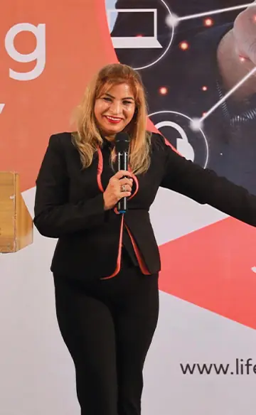 Anu Manocha in a black suit hosting a corporate event