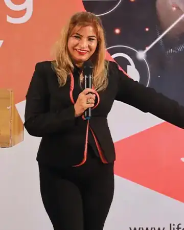 Anu Manocha in a black suit hosting a corporate event