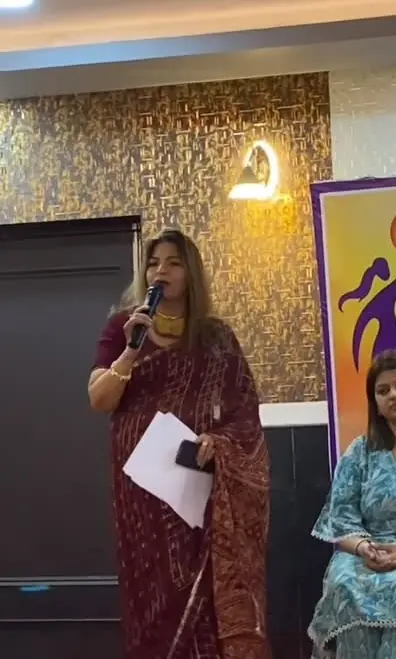 Anu Manocha at the mic hosting a women's foundation event