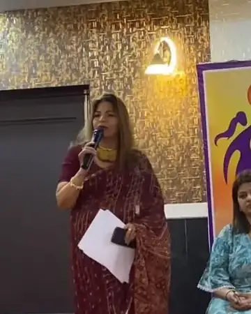 Anu Manocha at the mic hosting a women's foundation event