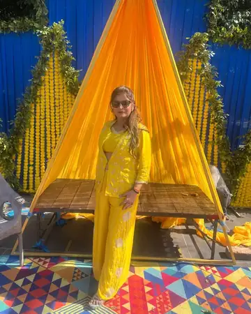 Anu Manocha at a haldi setup with a yellow drape and marigolds