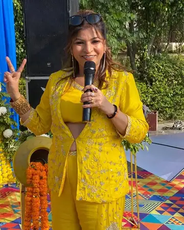 Anu Manocha smiling with mic at a haldi ceremony