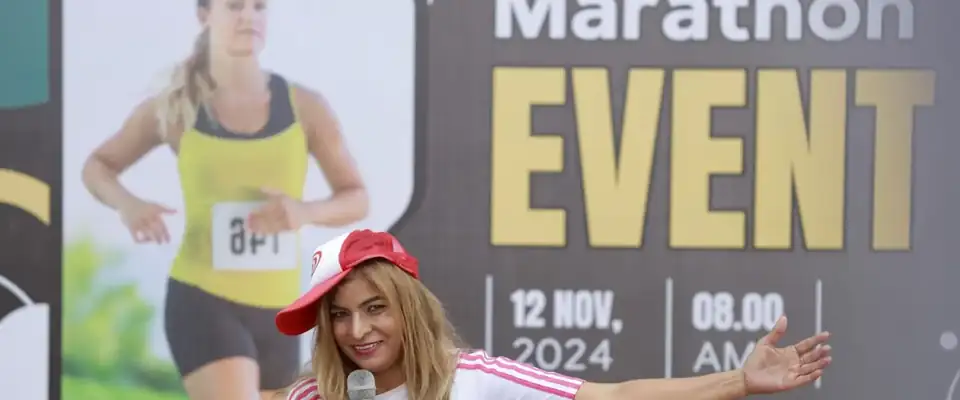 Anu Manocha hosting a marathon event with mic and cap