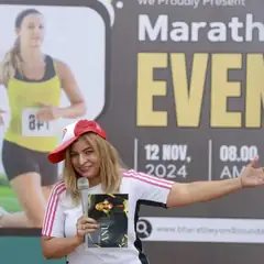 Anu Manocha hosting a marathon event with mic and cap