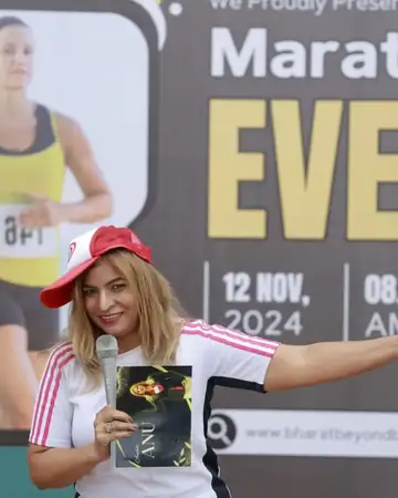 Anu Manocha hosting a marathon event with mic and cap