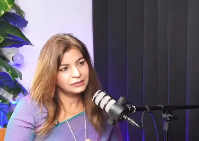Anu Manocha speaking into a studio microphone during a podcast