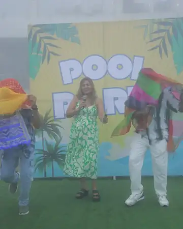 Anu Manocha on stage with guests at a pool party