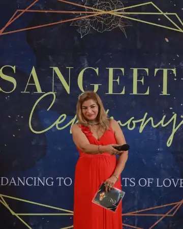 Anu Manocha at a Sangeet Ceremony backdrop holding her script