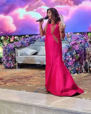 Anu Manocha in a pink gown hosting a sangeet in front of a floral stage