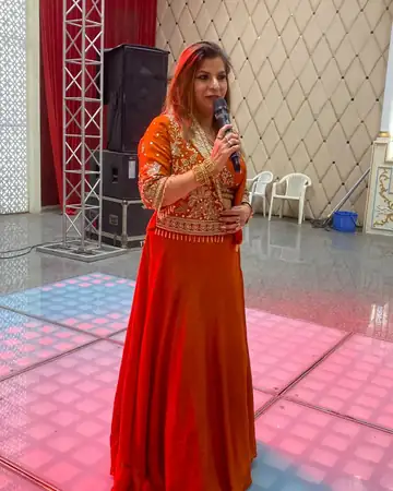 Anu Manocha anchoring a sangeet on a lit dance floor