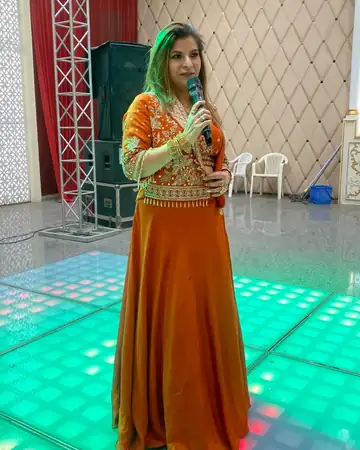 Anu Manocha hosting on a green-lit sangeet dance floor