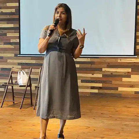 Anu Manocha giving the welcome address at a seminar in Delhi, in front of a projector screen