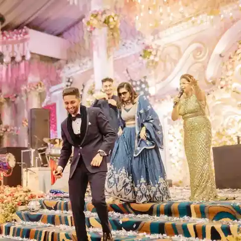 Anchor Anu Manocha with the mic as the couple makes their stage entry at a wedding sangeet in Delhi NCR