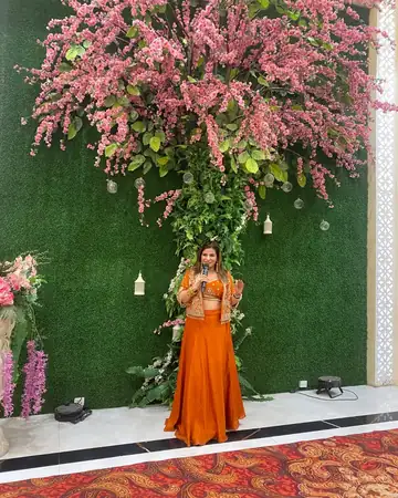 Anu Manocha in front of a floral wall at a wedding function