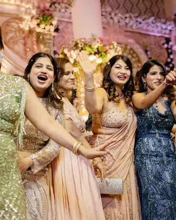 Anu Manocha leading a song with women guests on stage at a wedding sangeet night