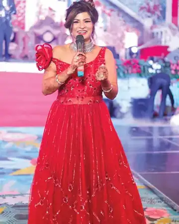Anu Manocha in a red gown speaking on a wedding stage